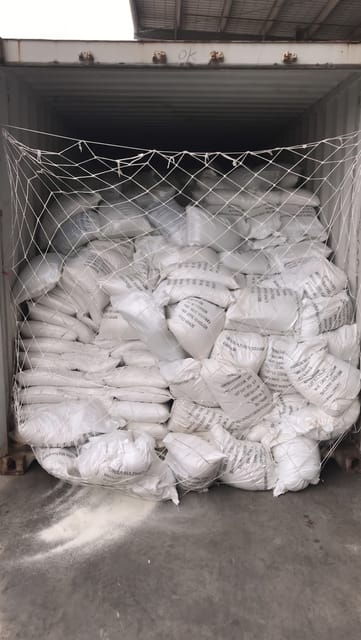 A ruptured bag at the bottom left of the container has caused product to spill onto the floor.