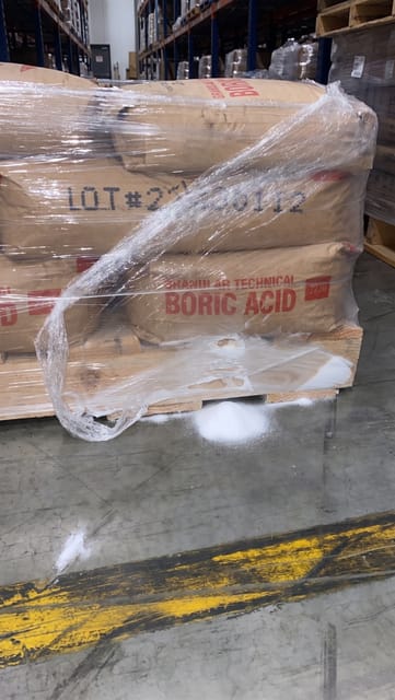 A bag of boric acid on the bottom layer of the pallet is torn, causing product to spill onto the pallet and the warehouse floor.